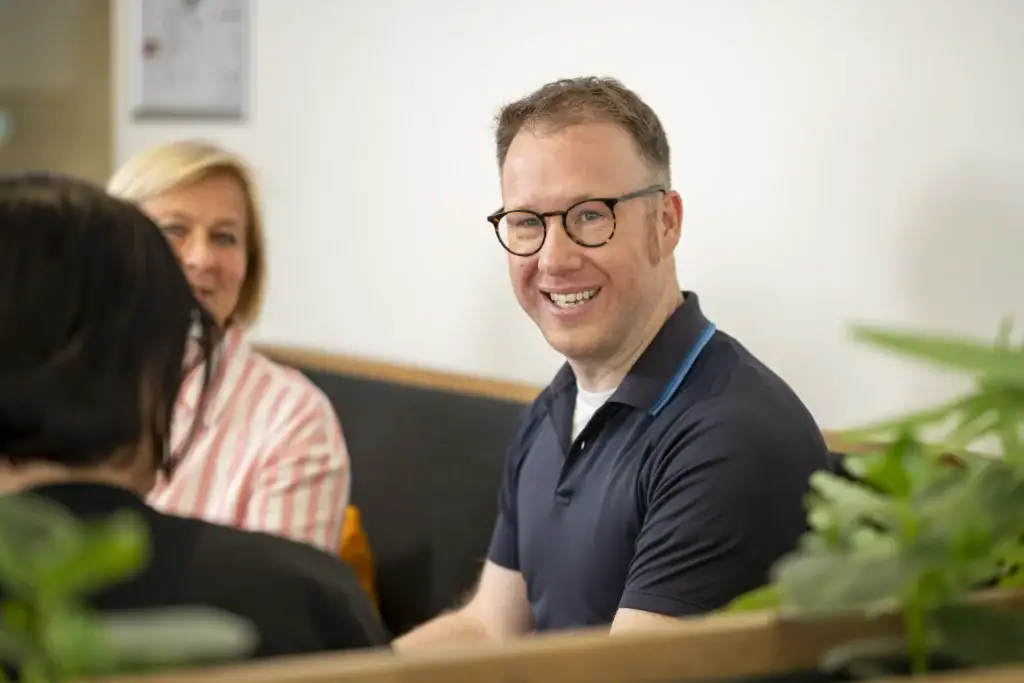 Mann mit Brille und Lächeln bei Neurodiversitäts-Workshop.