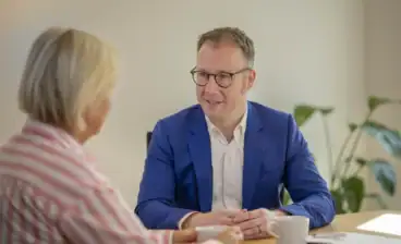 Mann im blauen Anzug spricht mit Frau bei Beratungsgespräch.